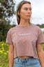 Close up of white embroidered design on a hazy pink crop top