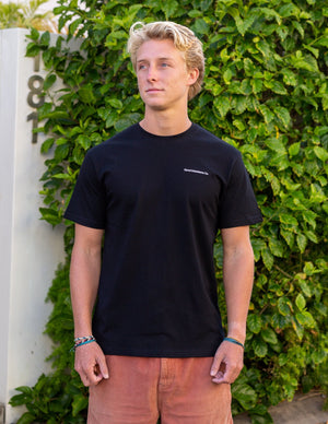 Man posing wearing black t-shirt with white embroidered design on it 