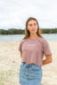 Woman on beach wearing hazy pink crop top